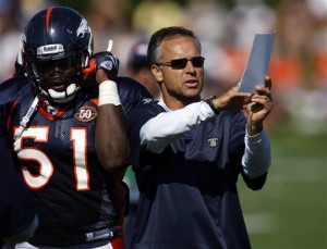 Denver Broncos defensive coordinator Mike Nolan, right, holds up a play diagram as rookie linebacker Lee Robinson heads to his position during drills at the opening day of training camp at the Broncos headquarters in the Denver suburb of Englewood, Colo., on Friday, July 31, 2009. (AP Photo/David Zalubowski)