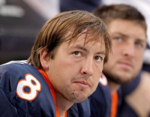 Kyle Orton and Tim Tebow look on from the bench during a 59-14 loss to the Oakland Raiders. (Photo by Justin Edmonds/Getty Images)